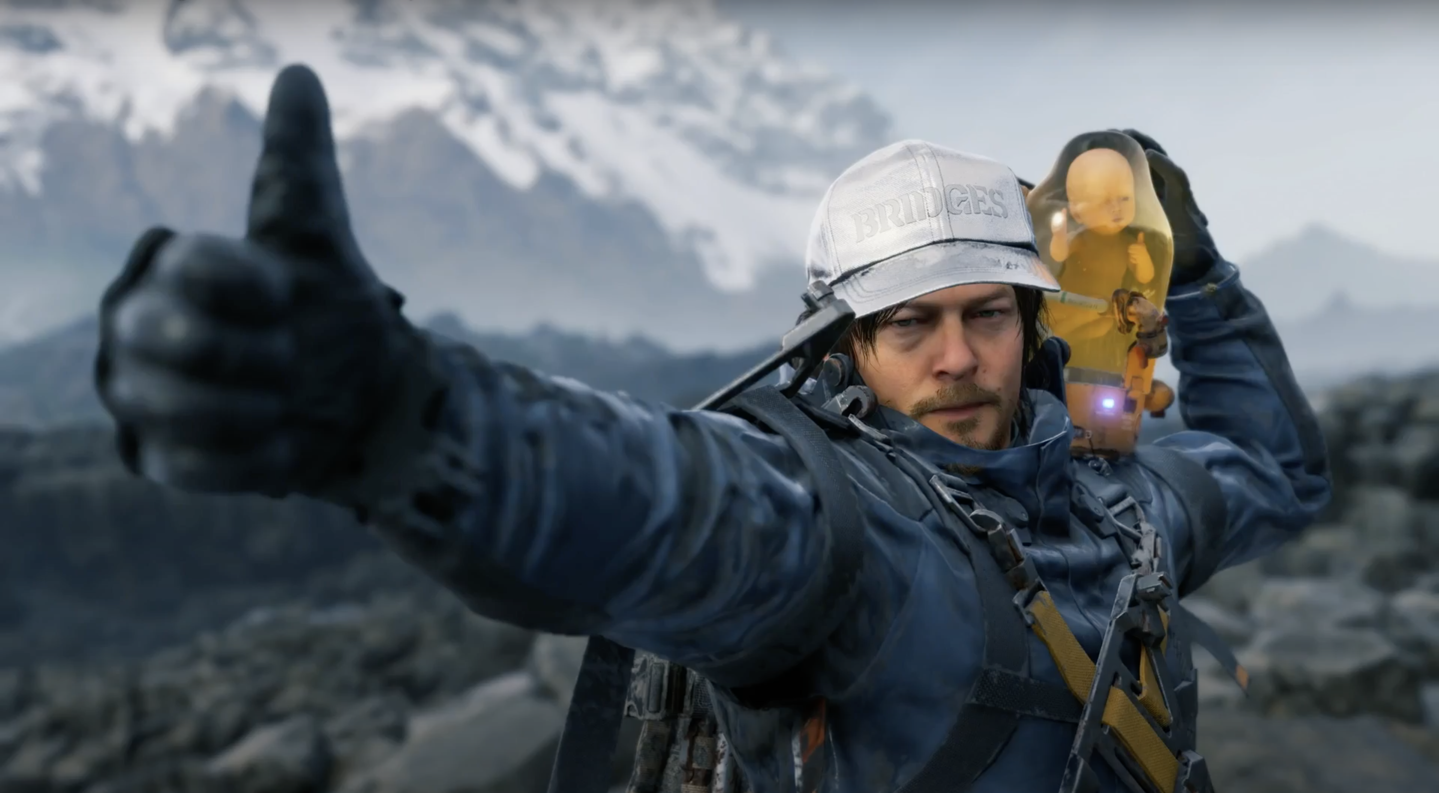 Death Stranding - Sam Porter carries a BB on his shoulder and gives a thumbs up to the camera.